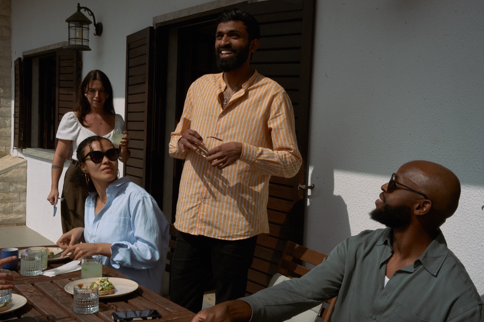A group around the outdoor table in the sun, plates and drinks